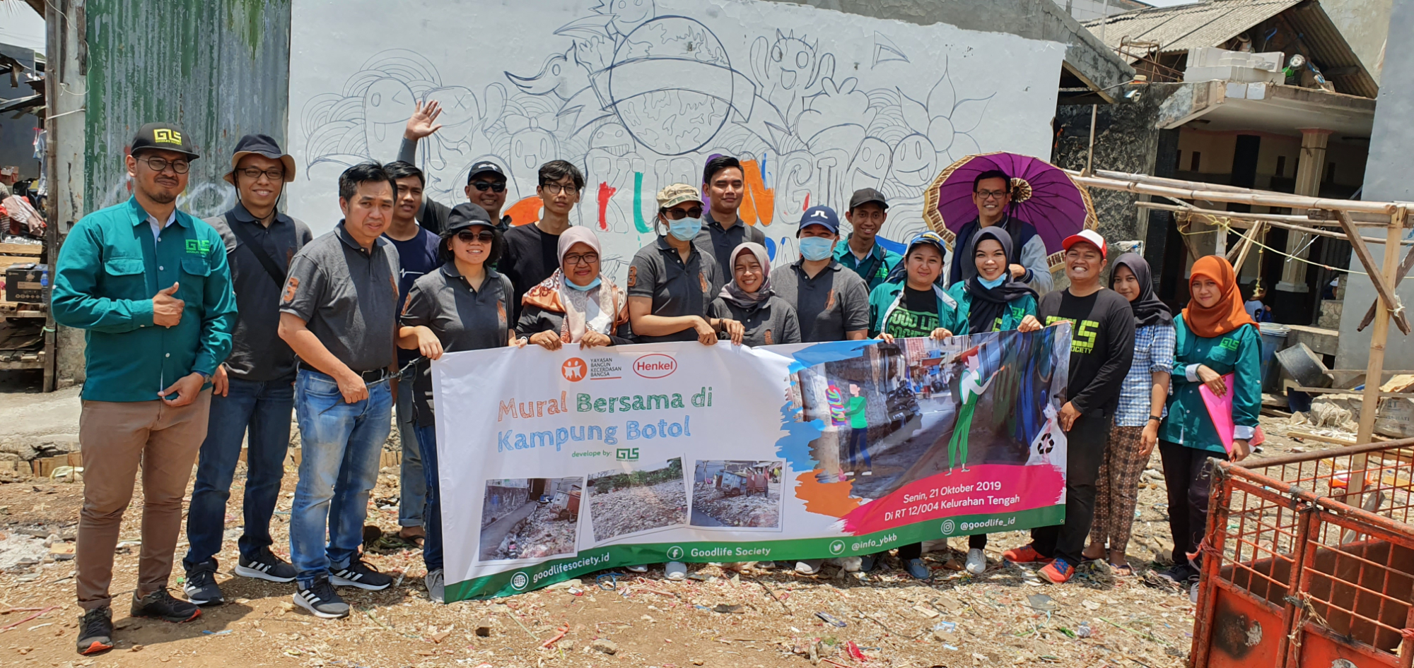 Our employees in front of the mural wall that reads “Kurangi Sampah Plastik”.