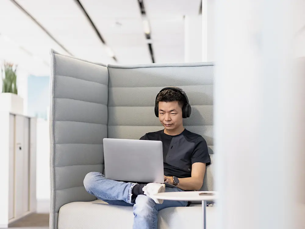 Seorang karyawan Henkel dengan headphone bekerja berkonsentrasi pada laptopnya. 