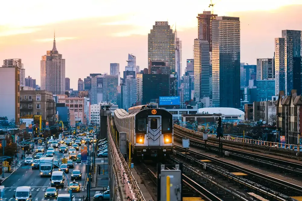 Kereta perkotaan melintas melalui cakrawala kota modern pada siang hari.
